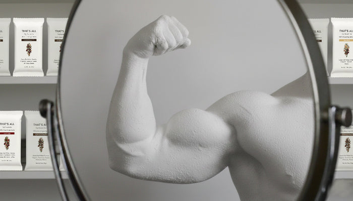 Muscular arm flexing in front of a mirror with Thats All Protein Bars in the background